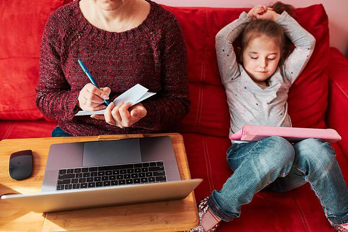 Une jeune fille sur sa tablette à côté de sa grand-mère sur son ordinateur